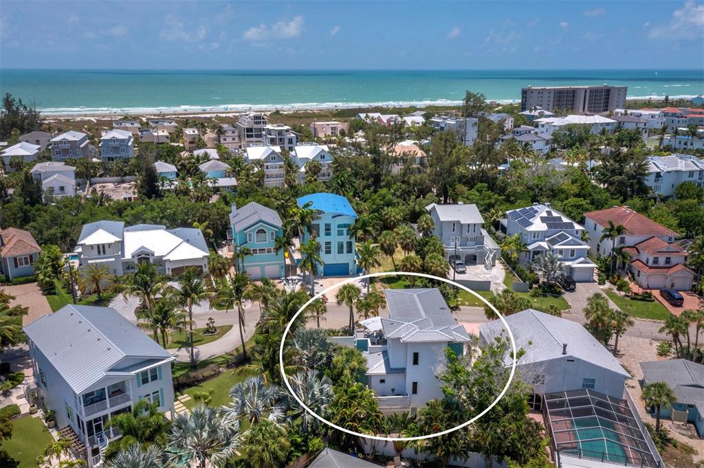 An aerial view of a coastal neighborhood featuring a white house circled in the foreground — 471 ISLAND CIRCLE, SARASOTA, FL
