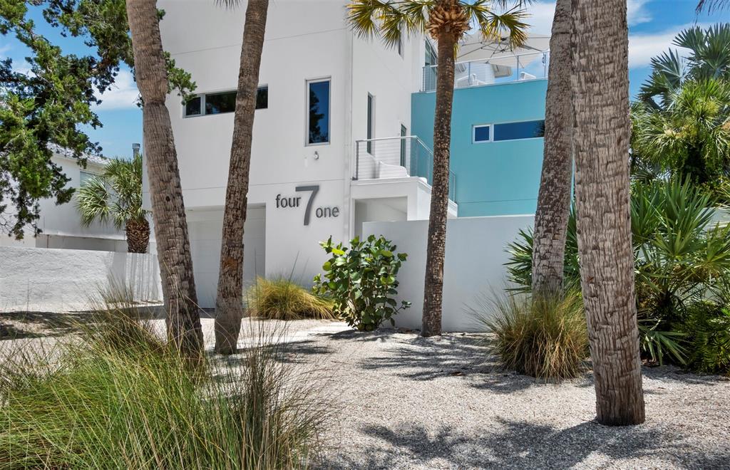 A modern white and teal house with palm trees and a gravel driveway — 471 ISLAND CIRCLE, SARASOTA, FL