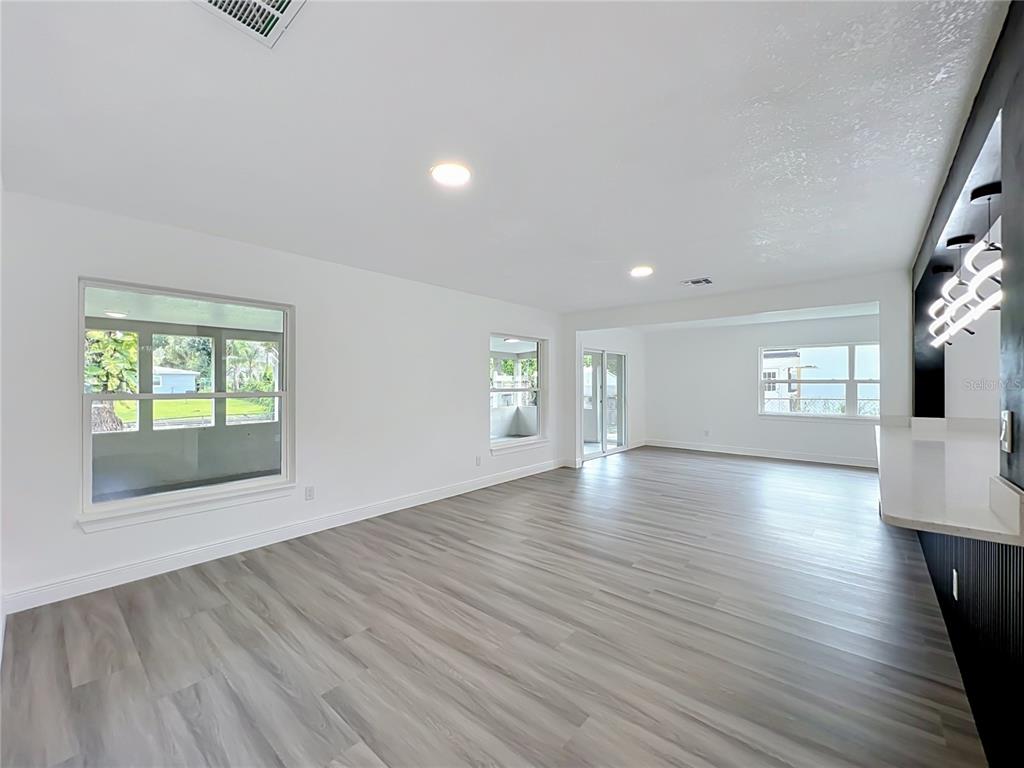 A bright, open-concept living area features white walls, recessed lighting, and light wood-look flooring — 3202 TRADEWINDS TRAIL, ORLANDO, FL