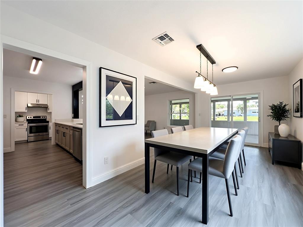 A dining room with a rectangular table and chairs sits adjacent to a modern kitchen — 3202 TRADEWINDS TRAIL, ORLANDO, FL