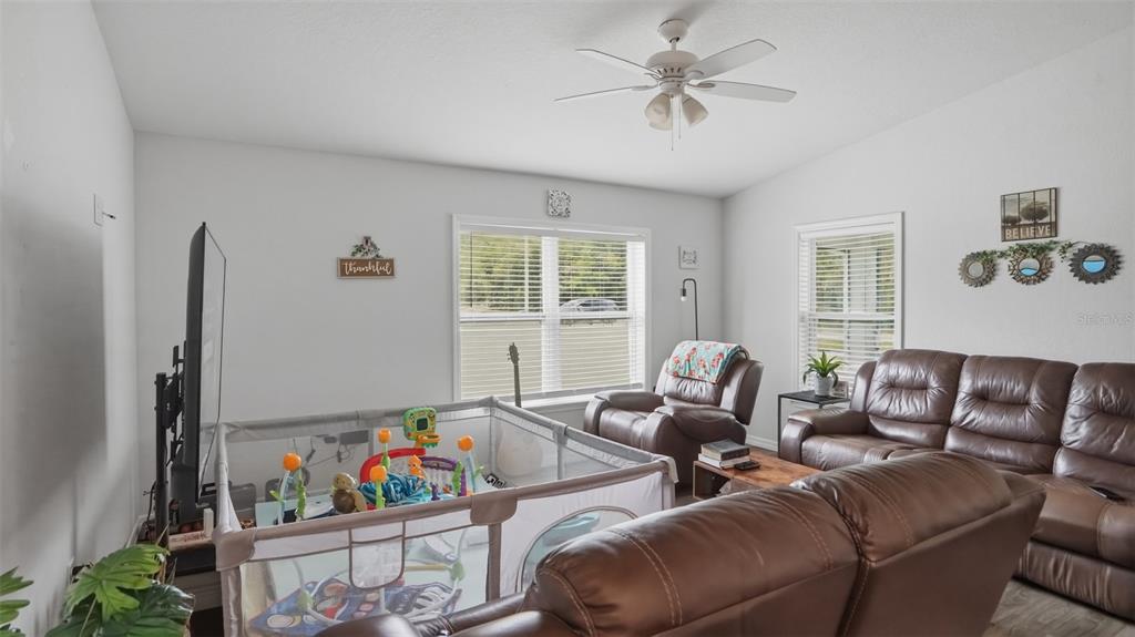 A living room features brown leather furniture, a playpen, and a ceiling fan — 30 MAPLE COURSE, OCKLAWAHA, FL