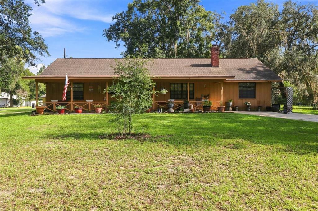 A single-story house with a wooden exterior, a front porch, and a brick chimney — 4553 E SHOREWOOD DRIVE, HERNANDO, FL