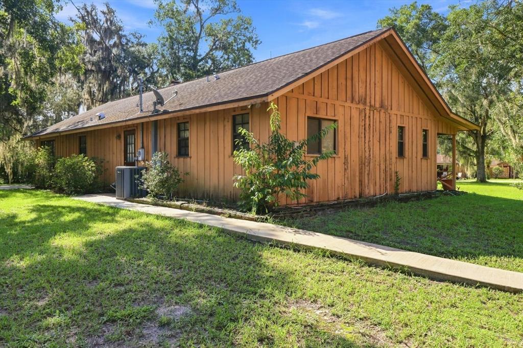 A side view of a single-story house with vertical wood siding and a concrete walkway — 4553 E SHOREWOOD DRIVE, HERNANDO, FL