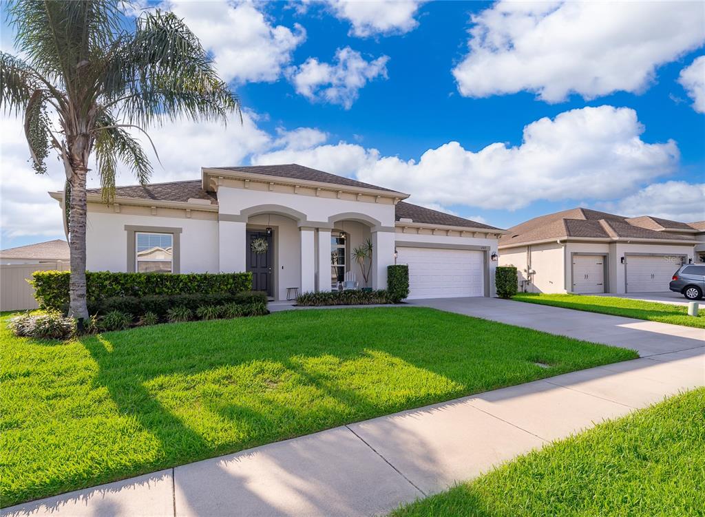 A single-story house with a white stucco facade, a two-car garage, and a palm tree — 1787 CHATSWORTH CIRCLE, ST CLOUD, FL