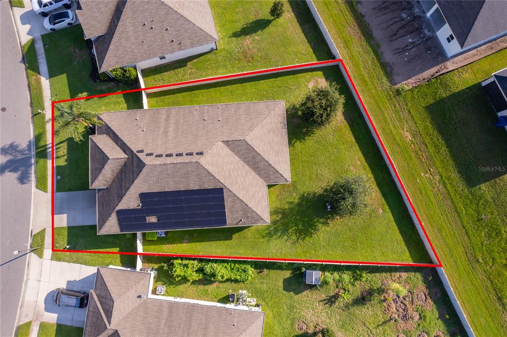 An aerial view shows a house with solar panels on a fenced, trapezoidal lot — 1787 CHATSWORTH CIRCLE, ST CLOUD, FL