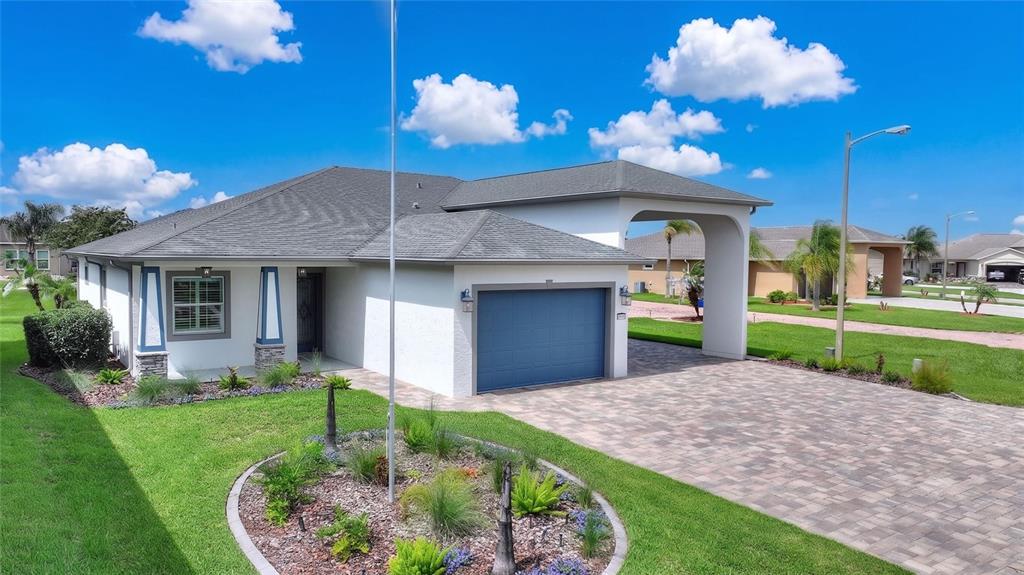 A single-story house with a blue garage, a paved driveway, and a circular garden bed — 716 TEABERRY TRAIL, POLK CITY, FL