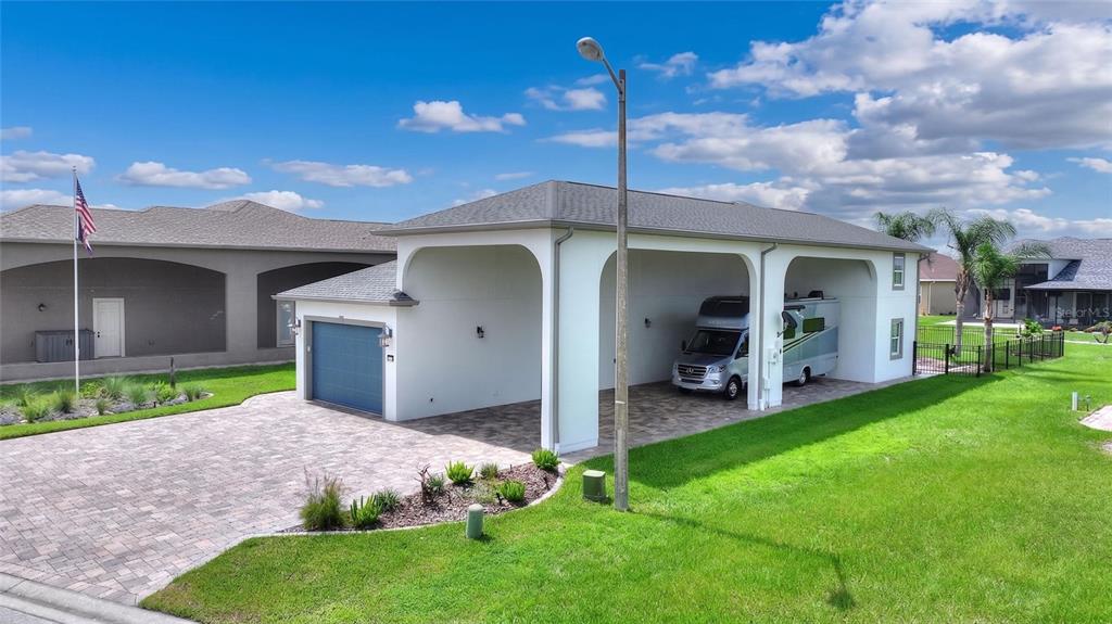 An exterior view of a house with a large attached RV carport and paved driveway — 716 TEABERRY TRAIL, POLK CITY, FL