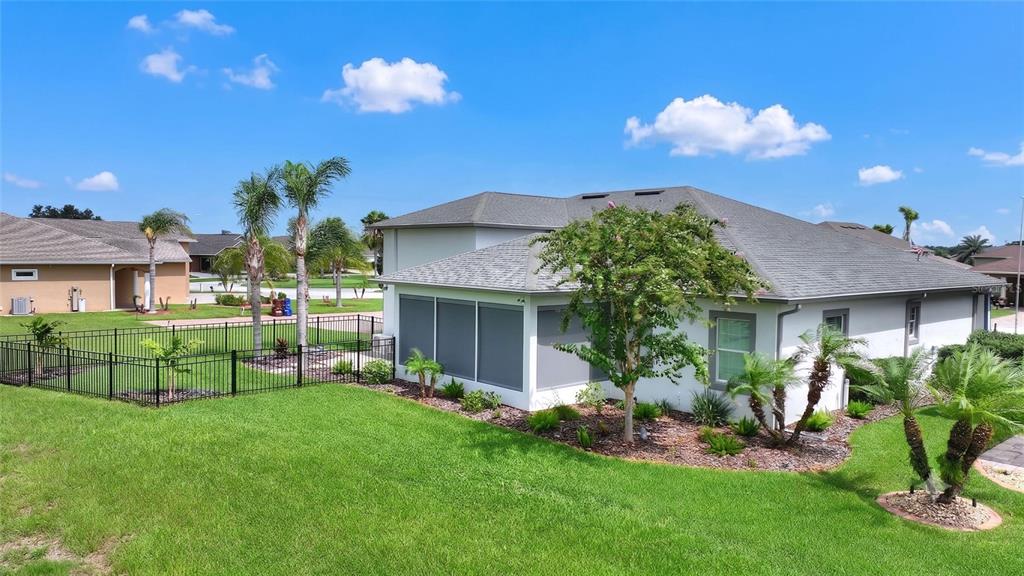 A house exterior features a screened-in patio, a fenced yard, and various palm trees — 716 TEABERRY TRAIL, POLK CITY, FL
