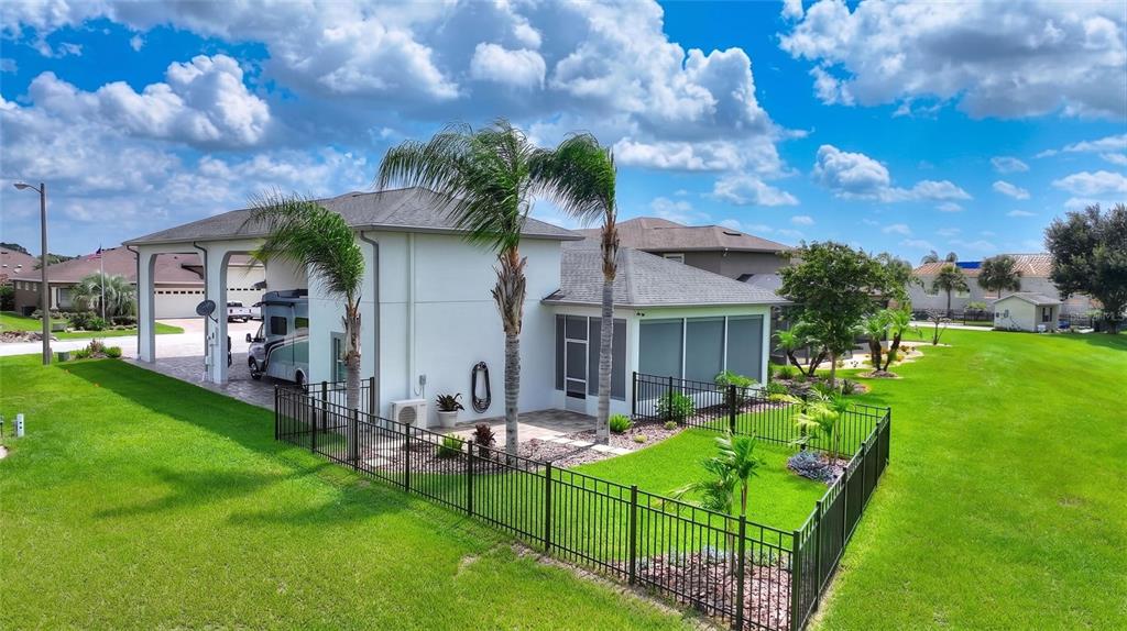 An exterior view of a house with a screened-in porch, palm trees, and fenced yard — 716 TEABERRY TRAIL, POLK CITY, FL