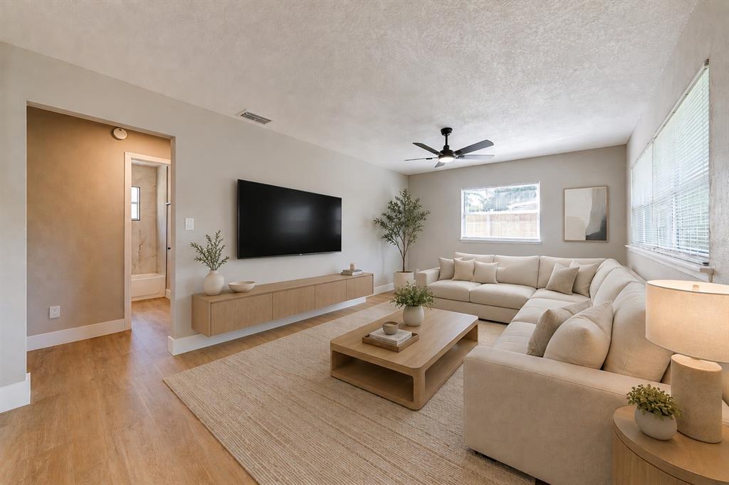 A living room features a wall-mounted television, floating console, sectional sofa, and light wood flooring — 703 S DIXIE AVENUE, FRUITLAND PARK, FL