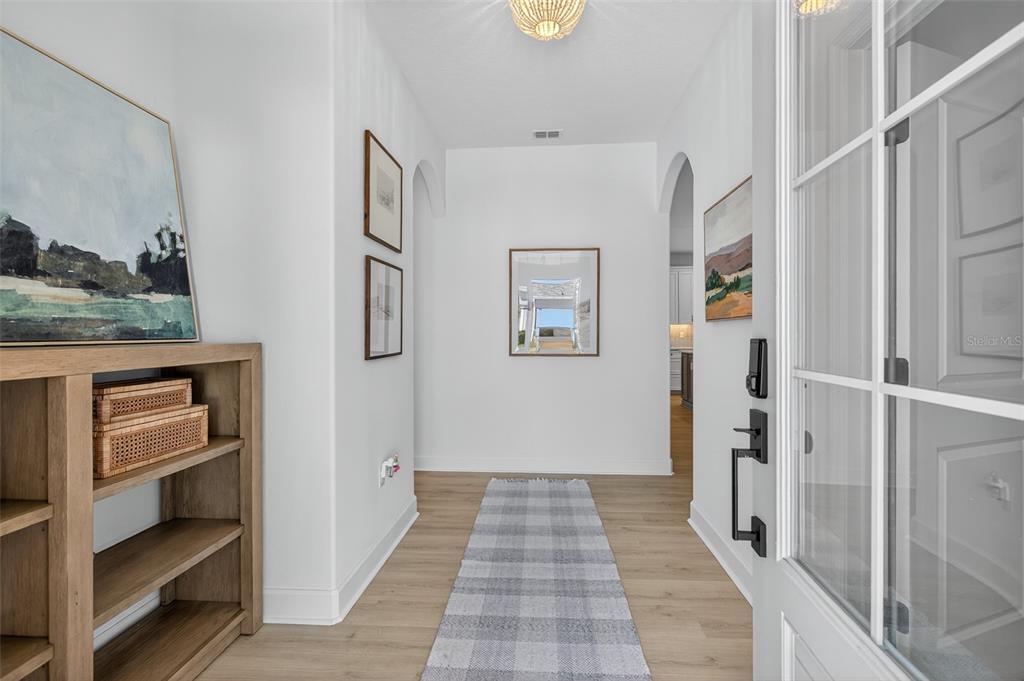 A bright entryway features light wood flooring, a plaid runner, and a wooden console table — 41 LA MANCHA DRIVE, PALM COAST, FL