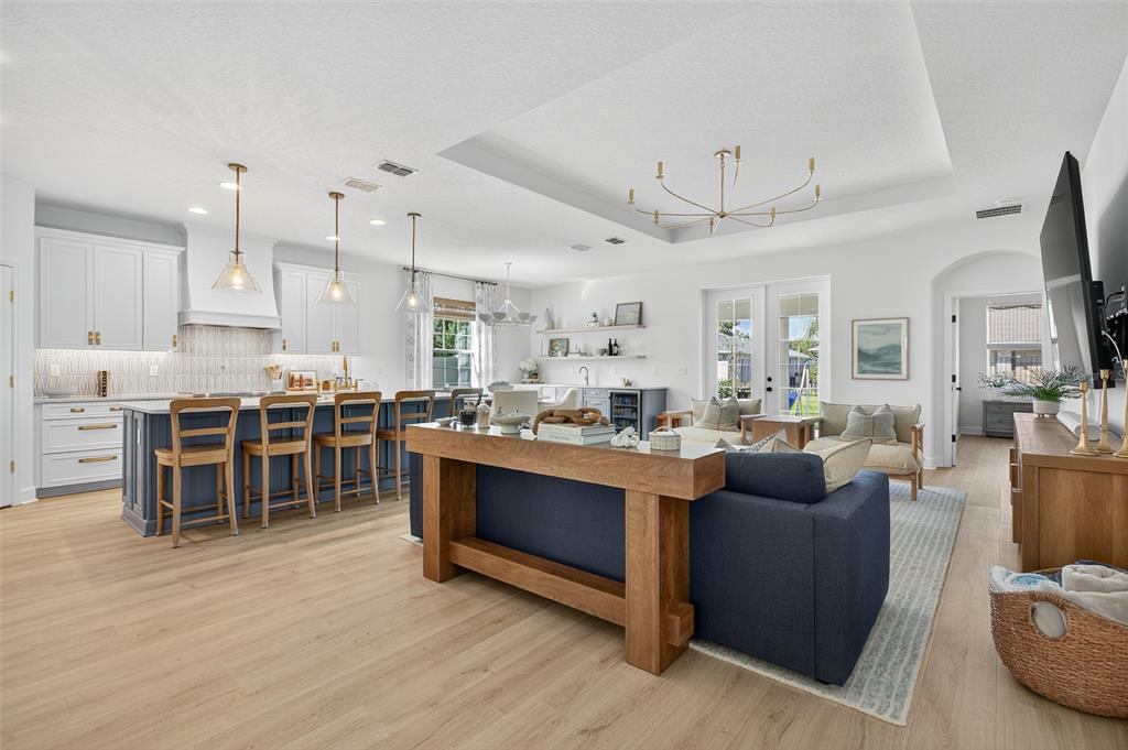 An open-concept kitchen and living area features a blue island, wood flooring, and pendant lighting — 41 LA MANCHA DRIVE, PALM COAST, FL