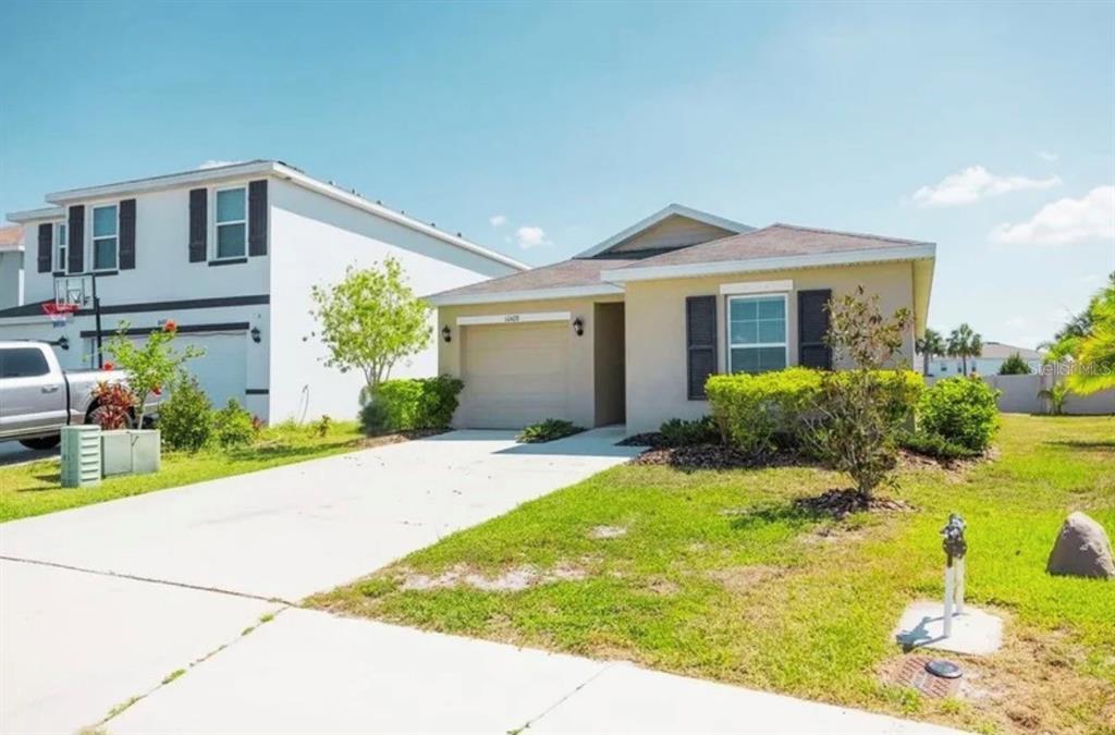 A single-story house with a beige exterior, a garage, and a concrete driveway — 10428 FLATHEAD DRIVE, PARRISH, FL