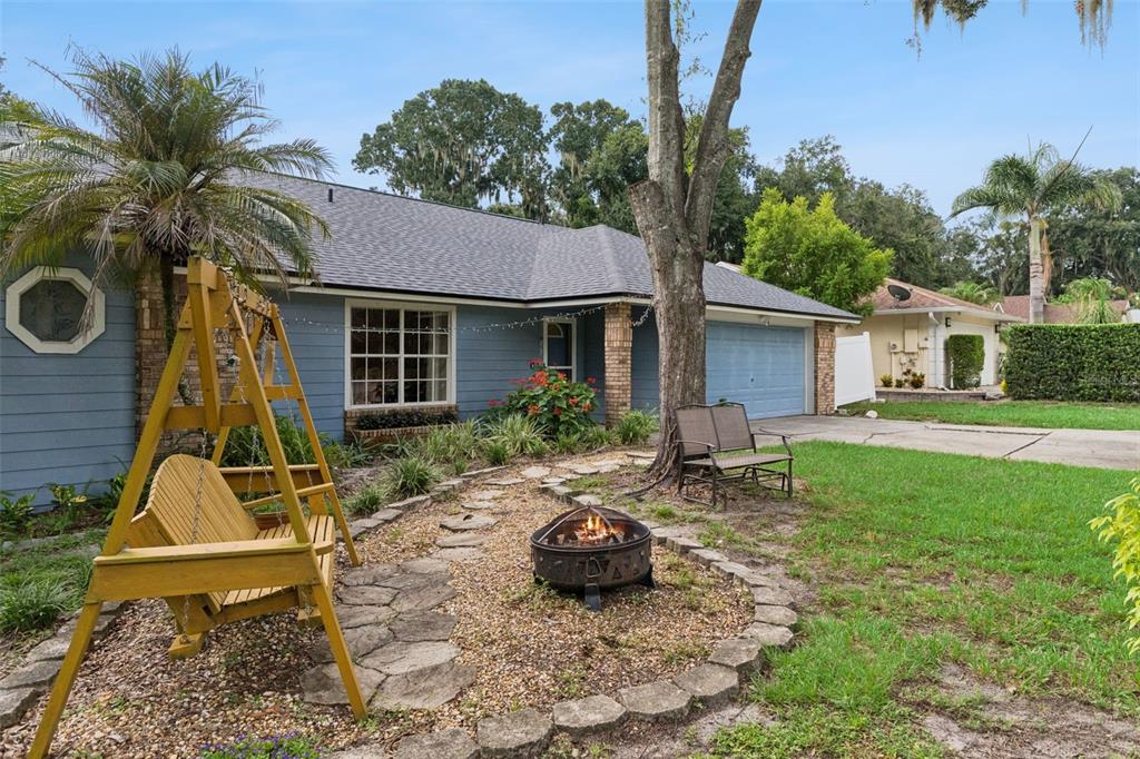 A blue house with a front yard fire pit, a wooden swing, and a driveway — 217 HARBOR DRIVE, WINTER GARDEN, FL