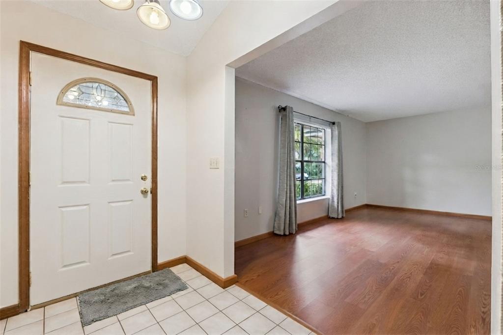 An entryway with a tiled floor leads into a living room featuring wood-look flooring — 217 HARBOR DRIVE, WINTER GARDEN, FL
