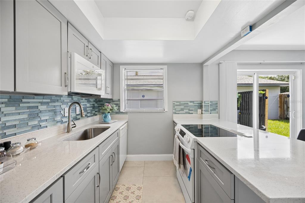 A kitchen with gray cabinets, white countertops, a breakfast bar, and a sliding glass door — 536 HIBISCUS WAY UNIT 7B, ORLANDO, FL