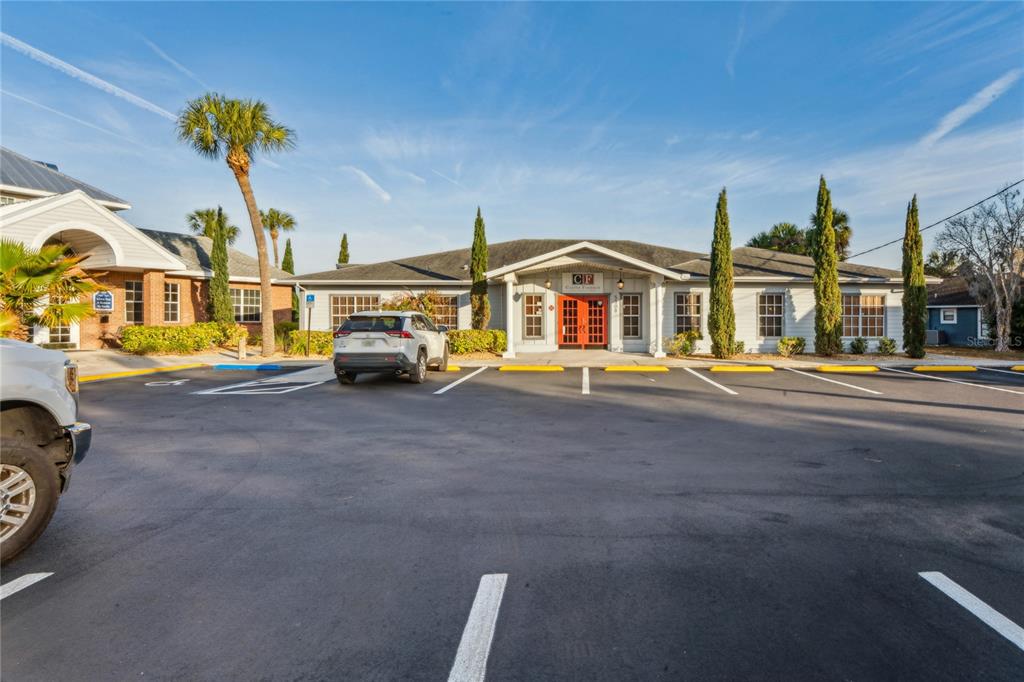 A single-story commercial building with a red entrance door and a parking lot in front — 5300 SPRING HILL DRIVE, SPRING HILL, FL