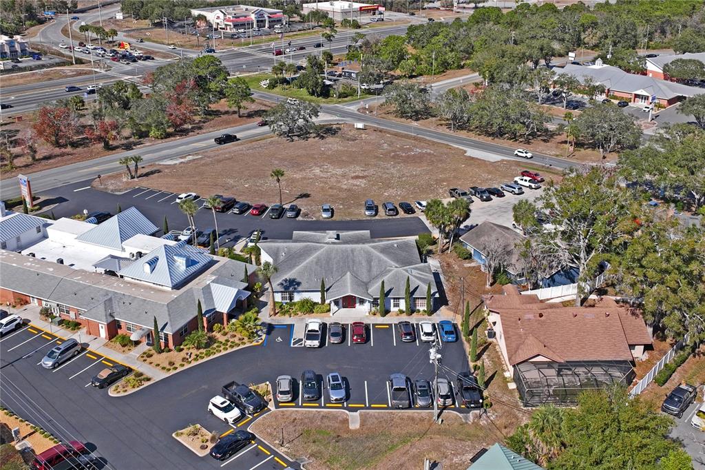 An aerial view shows a commercial building with a parking lot and an adjacent vacant lot — 5300 SPRING HILL DRIVE, SPRING HILL, FL