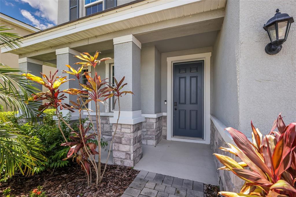 A gray front door with a stone base and porch columns under a covered entryway — 17828 GULF RANCH PLACE, LAKEWOOD RANCH, FL