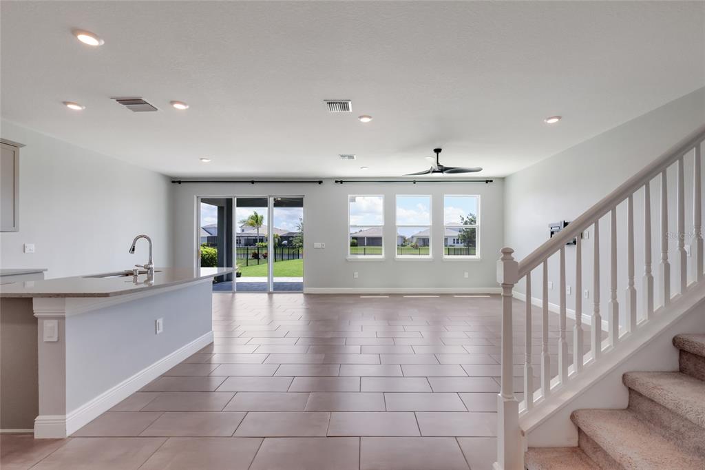 An open-concept living area features tile flooring, a kitchen island, and a staircase with carpet — 17828 GULF RANCH PLACE, LAKEWOOD RANCH, FL