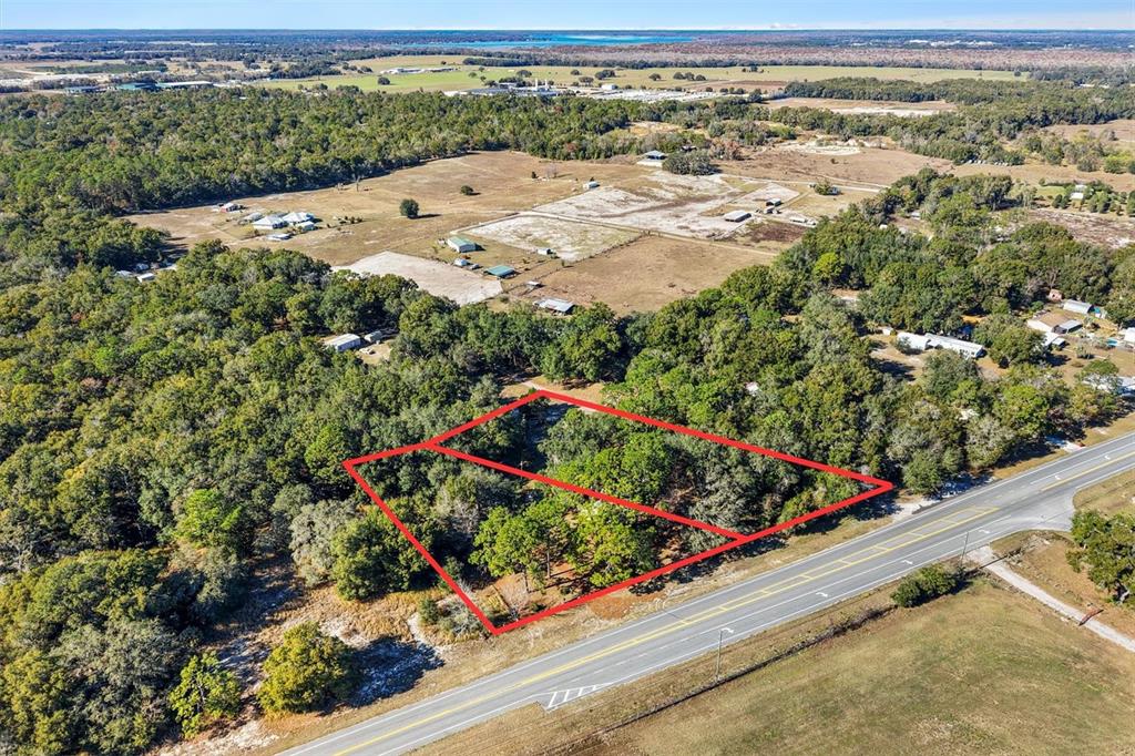An aerial view shows two adjacent, wooded, rectangular lots bordering a paved road — 00 S US 301, SUMTERVILLE, FL
