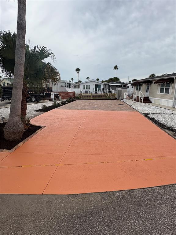 A paved driveway with a peach-colored concrete section and brick accents sits before several homes — 9000 US HIGHWAY 192 UNIT 327, CLERMONT, FL