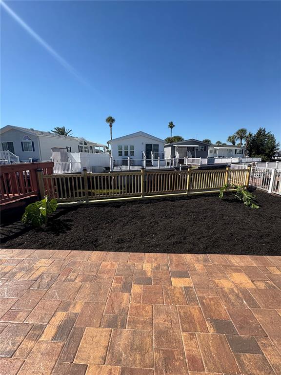A backyard features a stone paver patio, a wooden fence, and dark mulch with plants — 9000 US HIGHWAY 192 UNIT 327, CLERMONT, FL