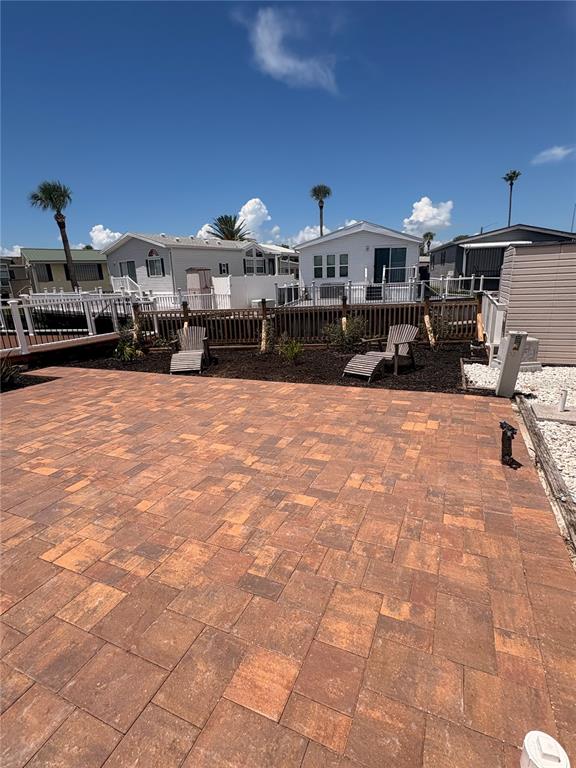 A paved patio area sits in front of a fenced yard with two outdoor chairs — 9000 US HIGHWAY 192 UNIT 327, CLERMONT, FL