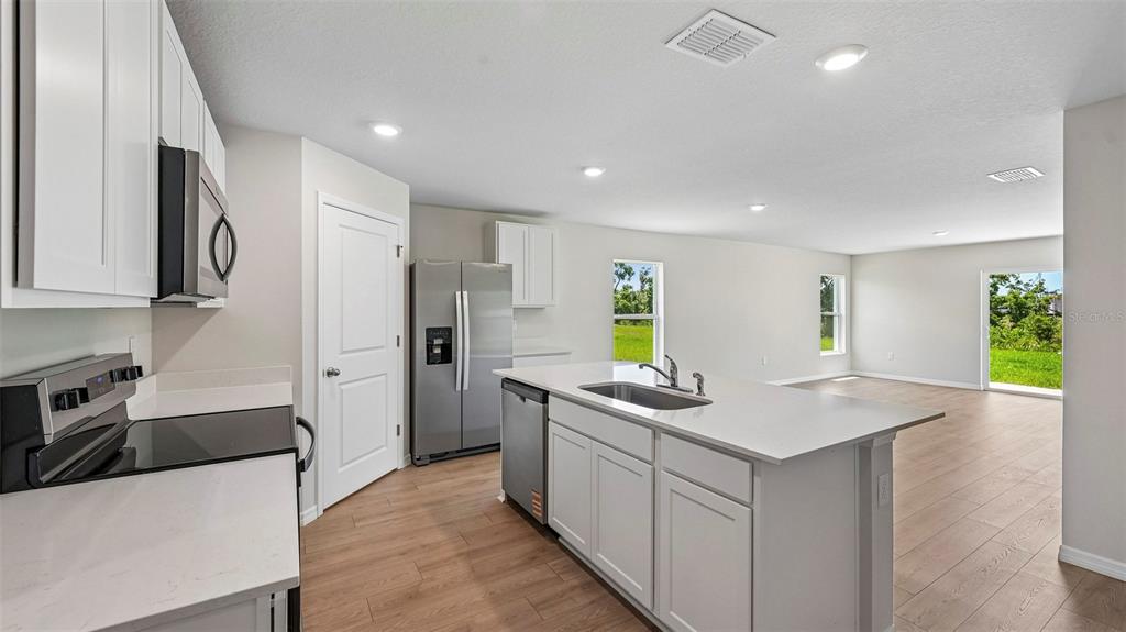 A modern kitchen with white cabinets, stainless steel appliances, and a central island with sink — 1142 BOURBON AVENUE, PARRISH, FL