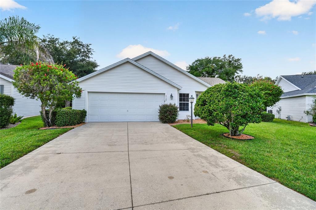A single-story house with white siding, a two-car garage, and a concrete driveway — 1745 LAKEWOOD DRIVE, THE VILLAGES, FL