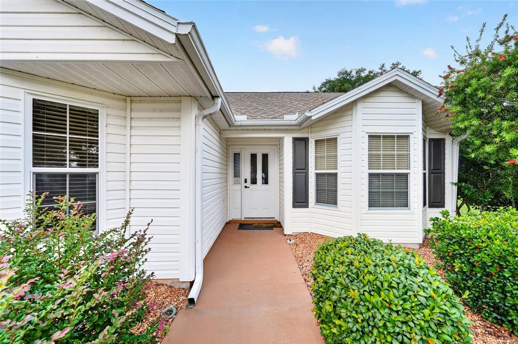 The exterior of a white-sided house features a front entrance with a concrete walkway — 1745 LAKEWOOD DRIVE, THE VILLAGES, FL
