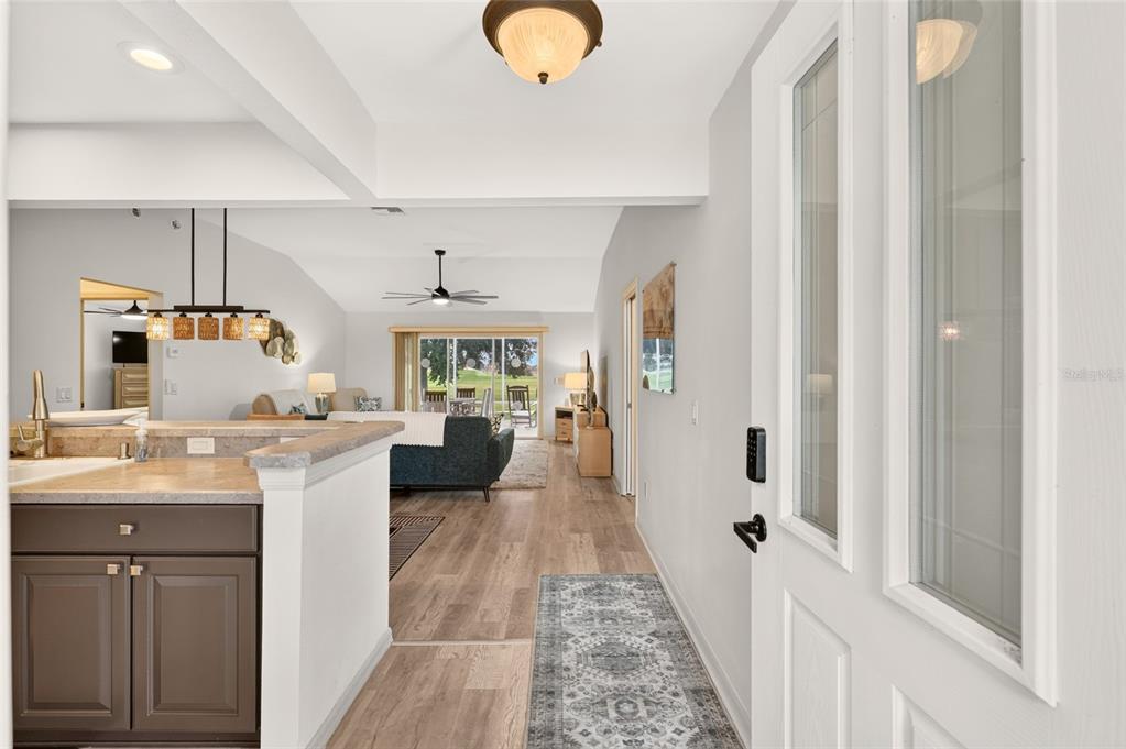 An entryway leads into an open-concept living area with wood-look flooring and a kitchen counter — 1745 LAKEWOOD DRIVE, THE VILLAGES, FL