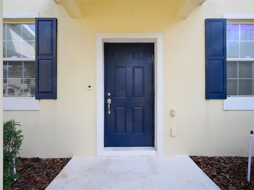 A dark blue front door is centered between two windows with blue shutters on a house — 1300 SEBURN ROAD, APOPKA, FL