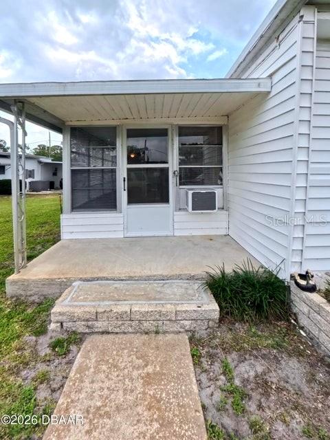A concrete walkway leads to a covered porch with a screen door and siding — 725 MARSHALL CIRCLE, PORT ORANGE, FL