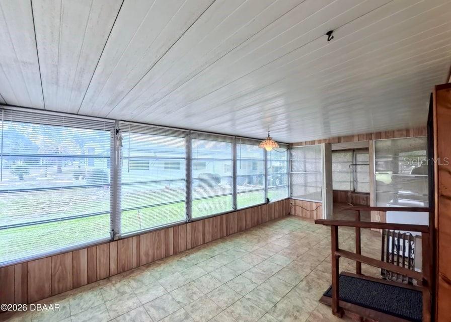 A sunroom features wood-paneled walls, a tiled floor, and large windows with blinds — 725 MARSHALL CIRCLE, PORT ORANGE, FL
