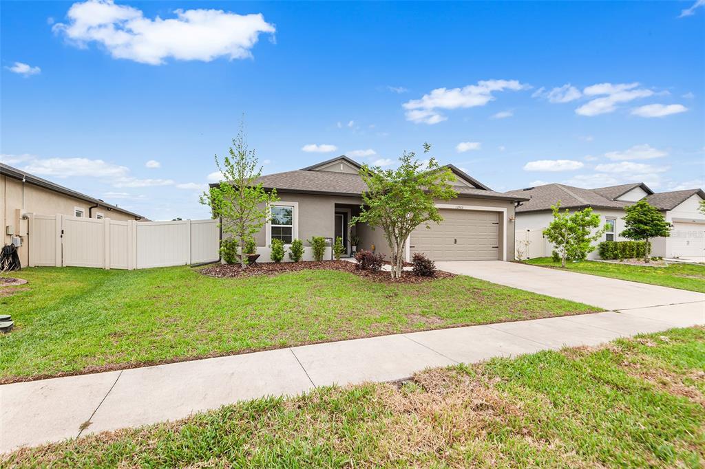 A single-story suburban house with a gray exterior, a two-car garage, and a front lawn — 12960 CONQUISTADOR LOOP, SPRING HILL, FL