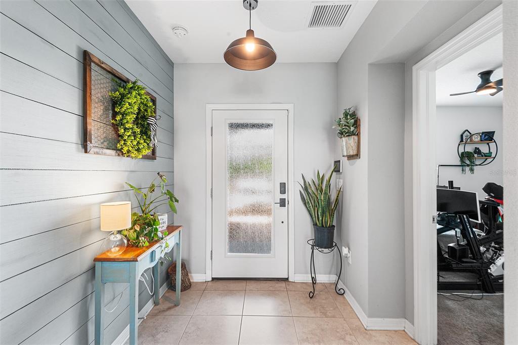 An entryway features a shiplap accent wall, a console table, and a glass-paneled front door — 12960 CONQUISTADOR LOOP, SPRING HILL, FL