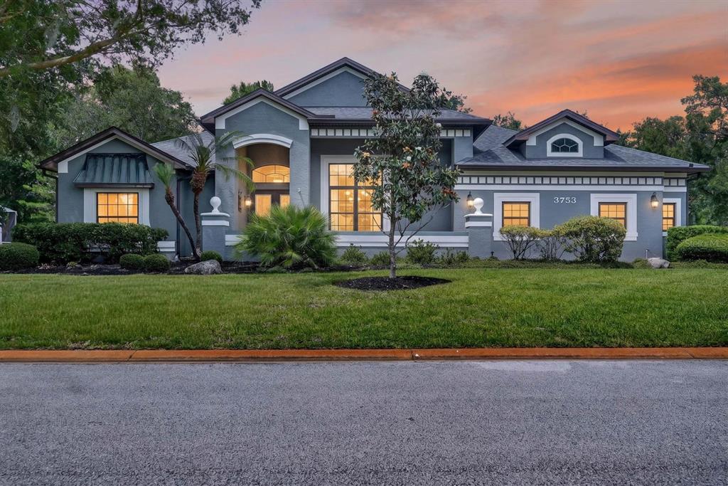 A single-story gray house with a gabled roof and a green lawn at sunset — 3753 MAYO CIRCLE, ORMOND BEACH, FL