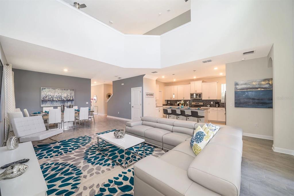 A spacious living room with high ceilings, a large sectional sofa, and an adjacent dining area — 2770 BOOKMARK DRIVE, KISSIMMEE, FL