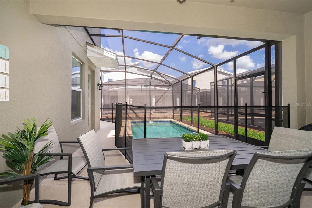 A bright, open-concept living and dining area features high ceilings, tile floors, and modern furniture — 2770 BOOKMARK DRIVE, KISSIMMEE, FL