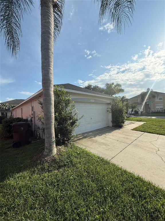 A single-story house with a white garage door and a palm tree in the front yard — 3059 BARBADOS LANE, HAINES CITY, FL