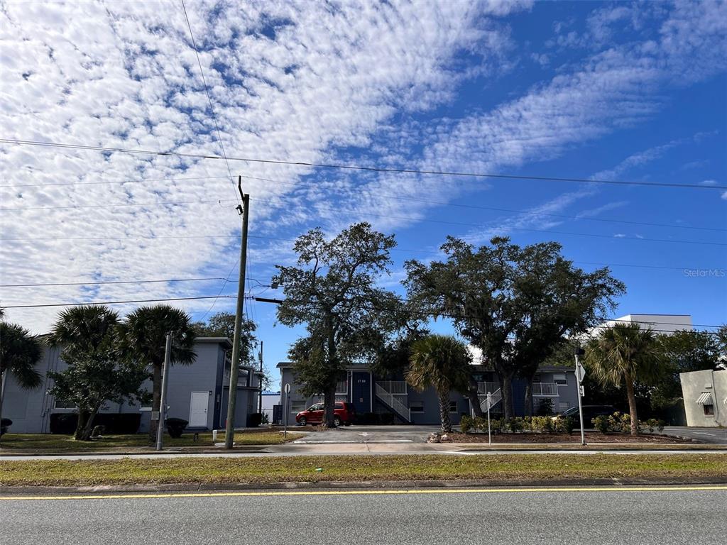 A two-story apartment building with a parking lot and trees under a blue sky — 1710 S WASHINGTON AVENUE UNIT 14, TITUSVILLE, FL