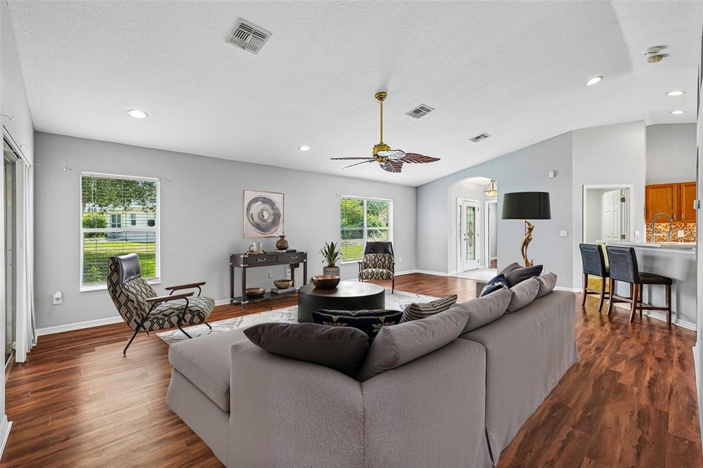 A living room with a gray sectional sofa, wood-look flooring, and a ceiling fan — 11455 INMAN COURT, SPRING HILL, FL