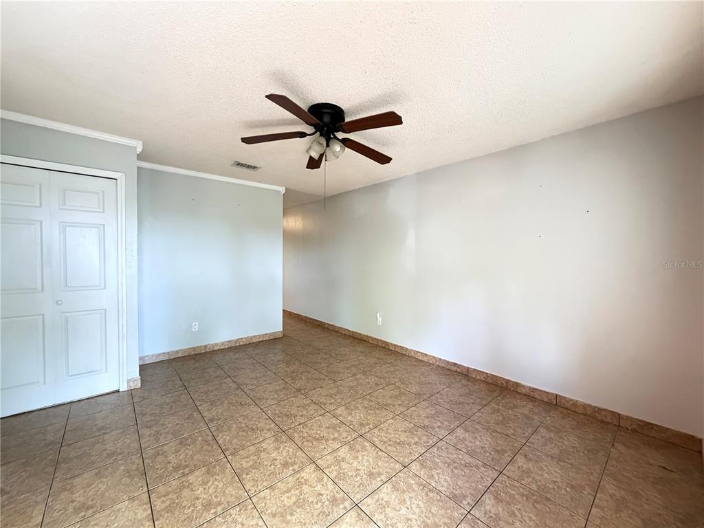 An empty room features light-colored walls, a ceiling fan, and brown tiled flooring — 84 E MARBRISA WAY, KISSIMMEE, FL