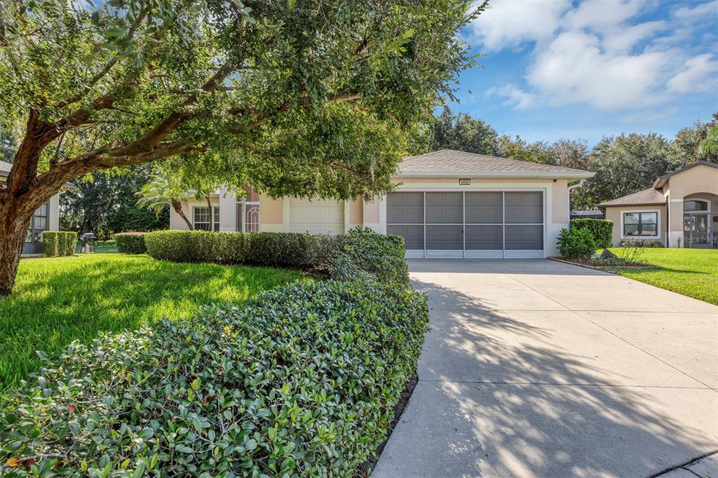 A single-story house with a concrete driveway, a two-car garage, and a manicured hedge — 4958 PORTSMOUTH STREET, TAVARES, FL