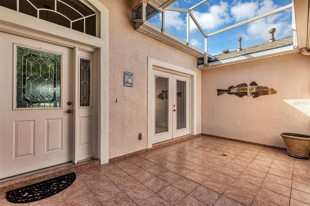 A tiled entryway features a front door, glass double doors, and a decorative fish wall hanging — 4958 PORTSMOUTH STREET, TAVARES, FL
