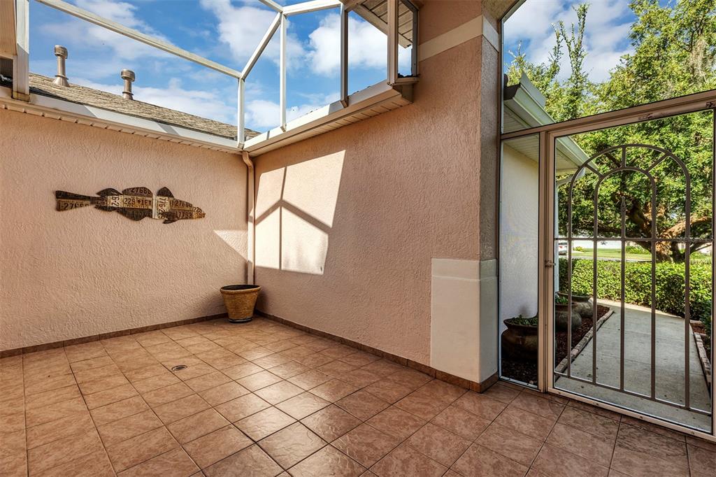 A tiled patio features a screened enclosure, a fish-shaped wall decoration, and a metal door — 4958 PORTSMOUTH STREET, TAVARES, FL