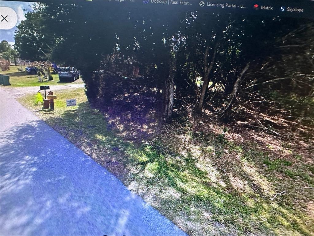A view of a wooded lot with a mailbox and a small sign near a road — 11335 EIGHTH AVENUE, PUNTA GORDA, FL