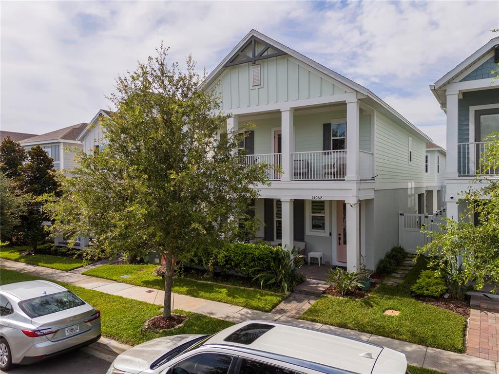 A two-story house with a light green exterior, a front porch, and a second-floor balcony — 15068 LEBEAU LOOP, WINTER GARDEN, FL