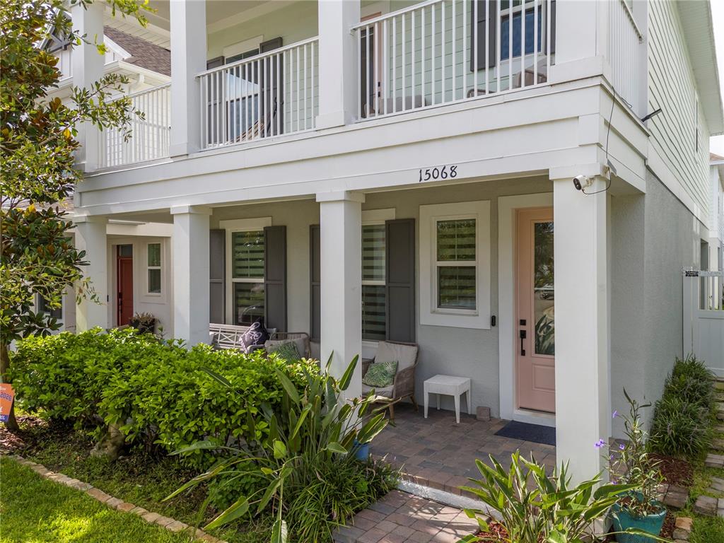 A two-story house features a covered front porch with a light pink door and columns — 15068 LEBEAU LOOP, WINTER GARDEN, FL
